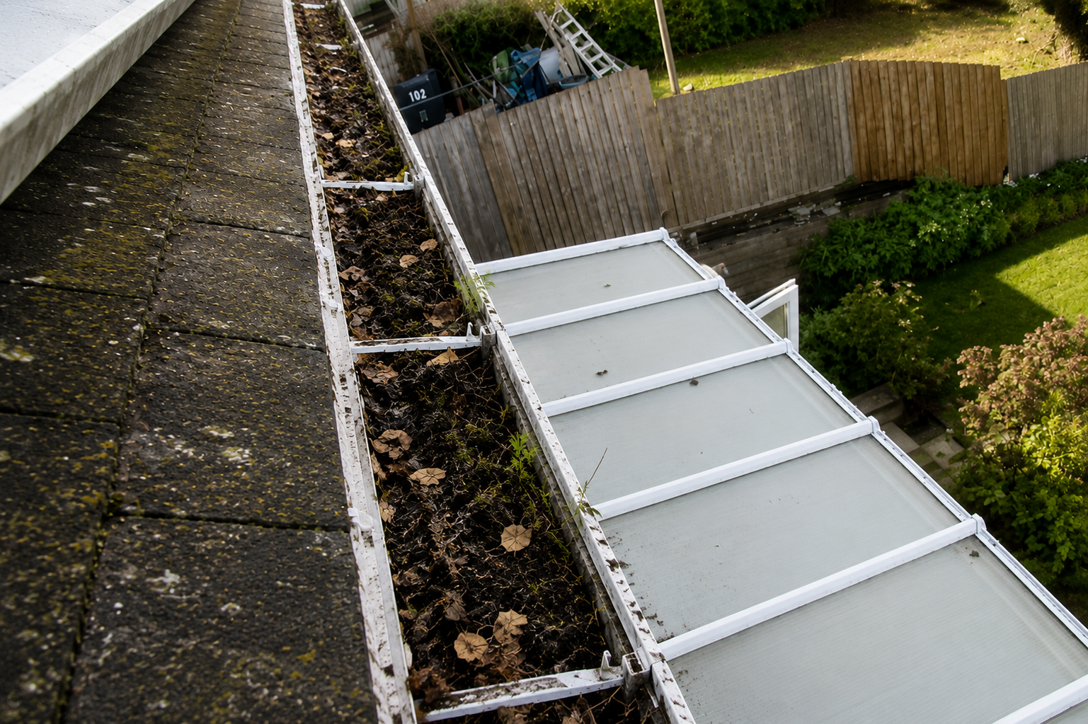 Blocked Birmingham gutter showing compacted debris and moss buildup before professional cleaning